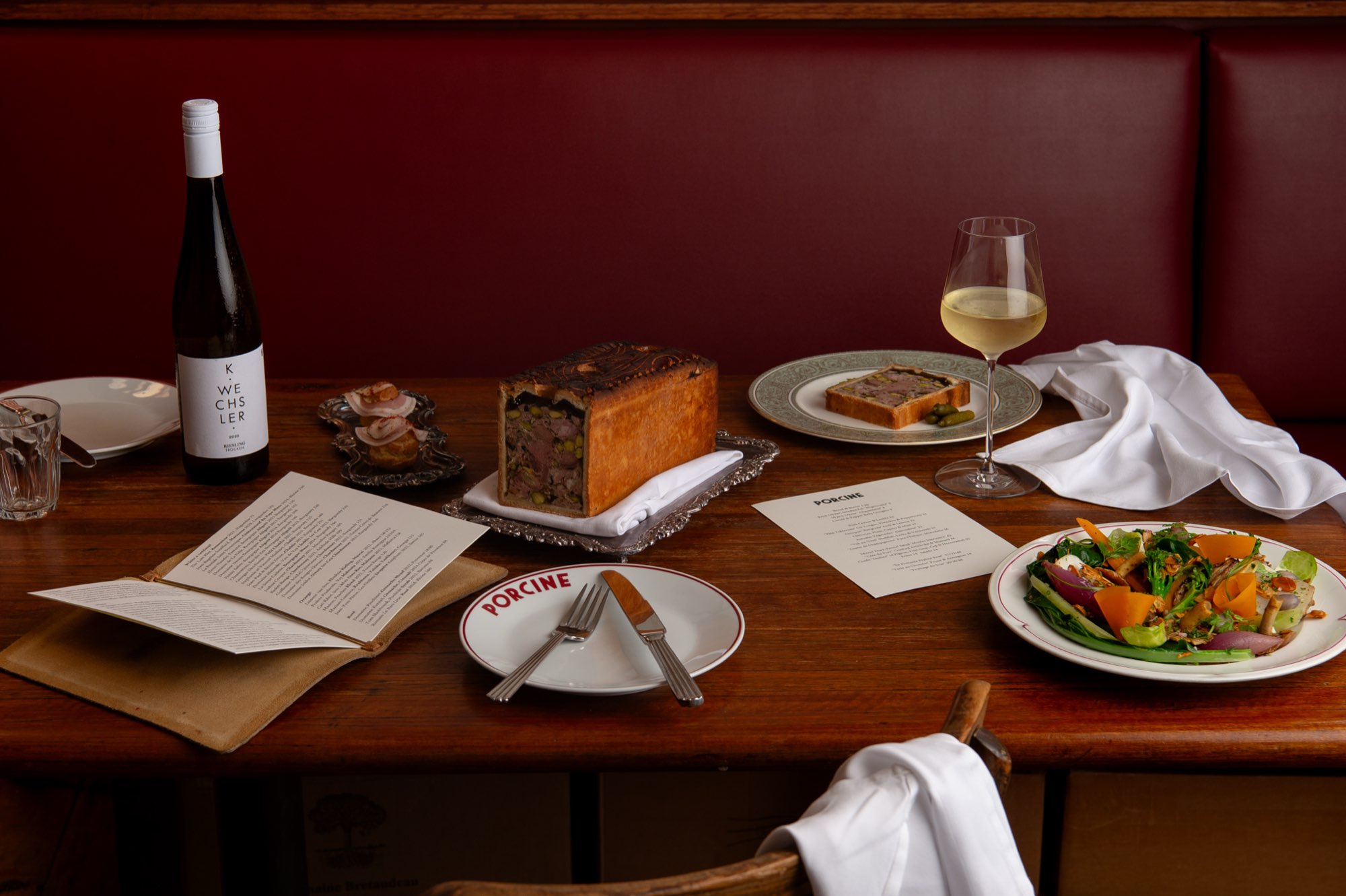 A table set against the red banquette at Porcine